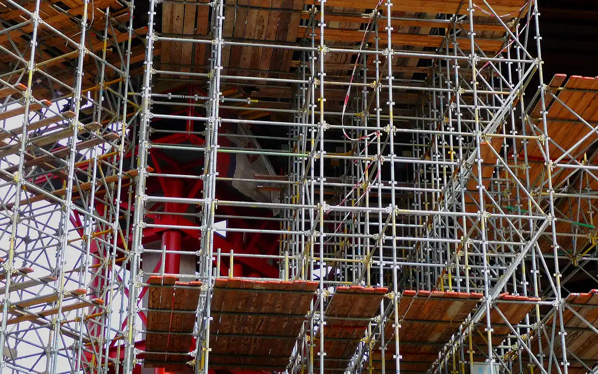 Andamio de tubos metálicos y tablones de madera cubriendo varios niveles de una obra en construcción.